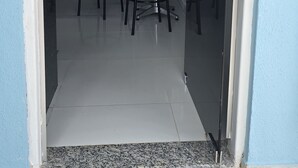 A room with a kitchenette, a dining area with two chairs, a bed, and a sliding glass door leading outside.