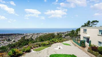 A residential area with a view of the ocean, a paved driveway, and a building with a balcony.