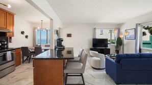 Een moderne keuken met een centraal eiland, een eethoek met stoelen, een bank en een televisie.