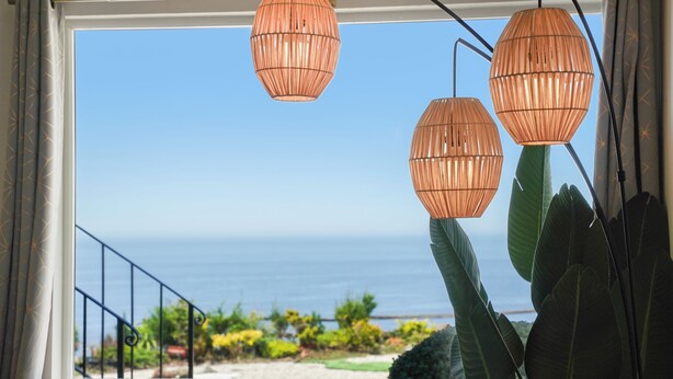 Een uitzicht op de oceaan, een hekwerk en hangende lampen.