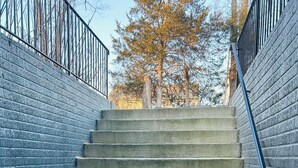 Een aantal betonnen traptreden met een metalen leuning, begrensd door blauwe bakstenen muren.