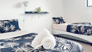 A modern bedroom with a bed, a bedside table, a wall-mounted shelf with decorative items, and a wall-mounted lamp. - A Quiet Modern / Brand New Gem (Lower Hutt)