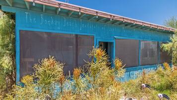 A building with large windows and a sign reading "The Bombay Beach Institute of Physical Metaphysics."
