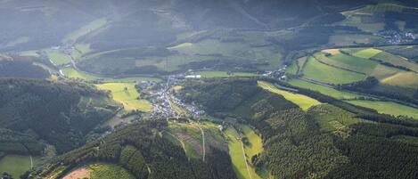 Une vue aérienne d’un paysage rural, avec des collines ondulantes, des champs et un petit village.