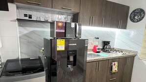 Eine kompakte Küche mit Kühlschrank, Mikrowelle und Kaffeemaschine.