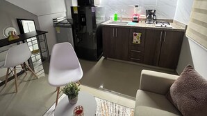 Eine moderne Küche mit dunklen Schränken, einem eingebauten Backofen und einer Arbeitsplatte mit Kaffeemaschine und Mixer.