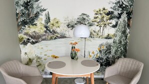 Ein Essbereich mit einem runden Tisch, zwei Stühlen, einer Lampe und einem Wandbild.