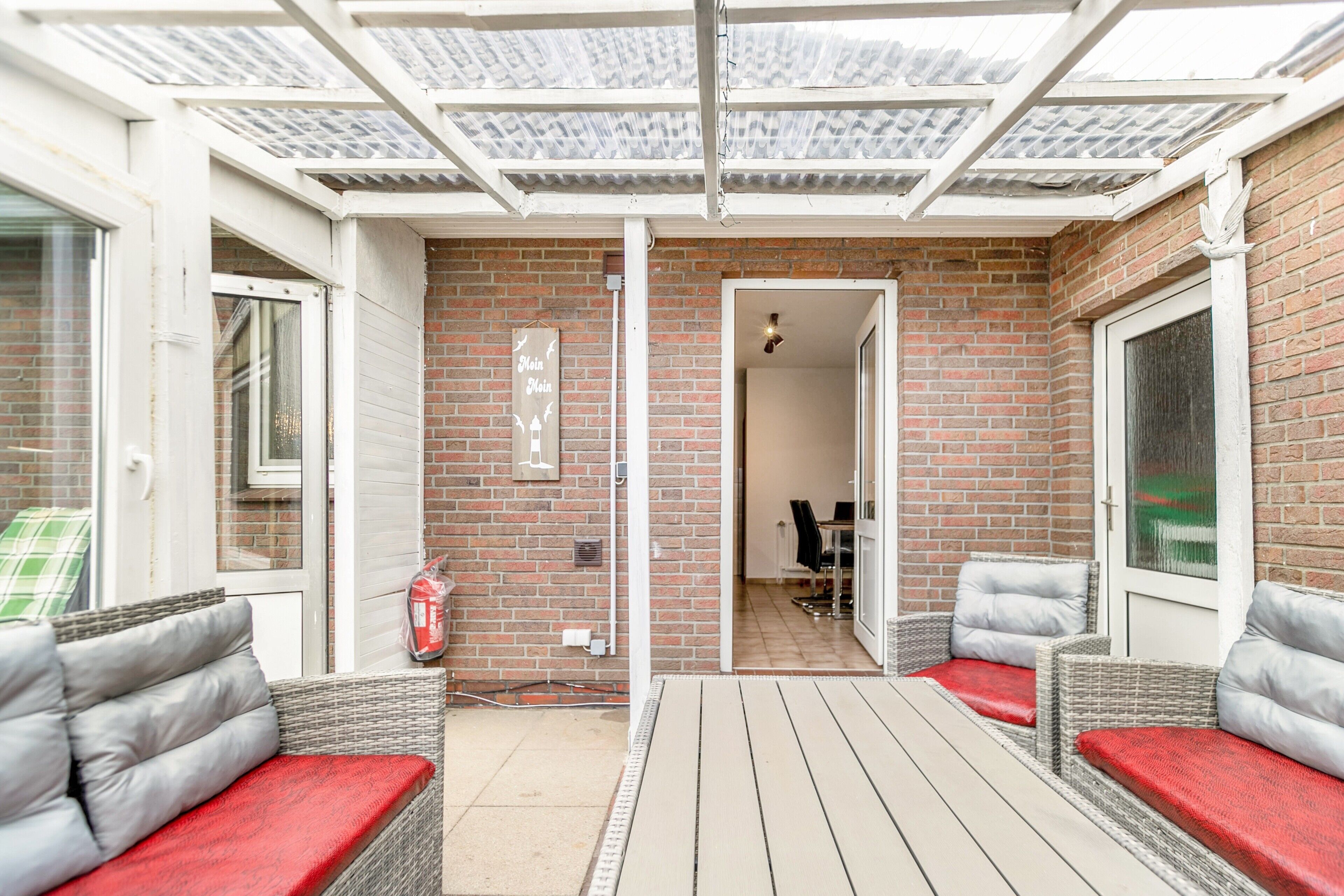 A covered patio area with wicker furniture and a brick wall.