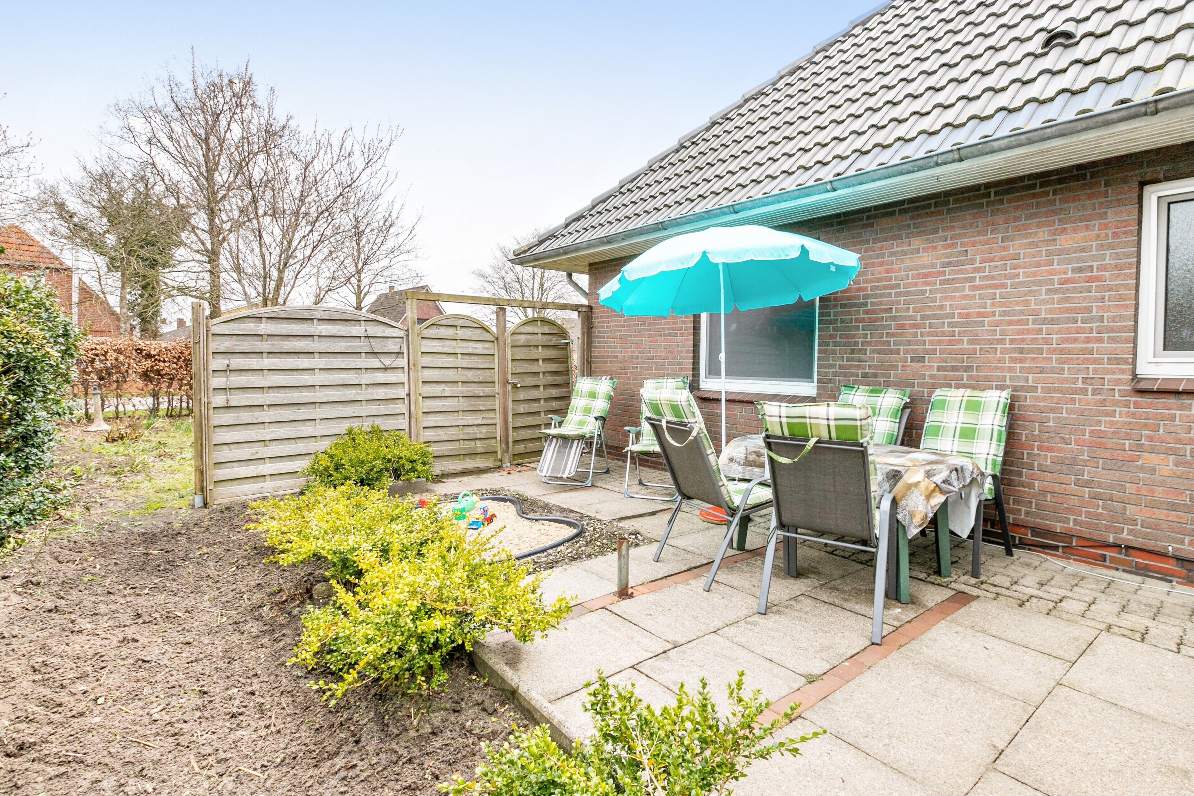 Een terras met een tafel, stoelen en een blauwe parasol.