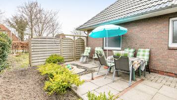 Een terras met een tafel, stoelen en een blauwe parasol.