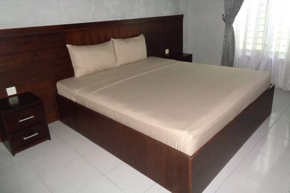 Un dormitorio con una cama grande, cabecera de madera, dos mesitas de noche y un tocador.