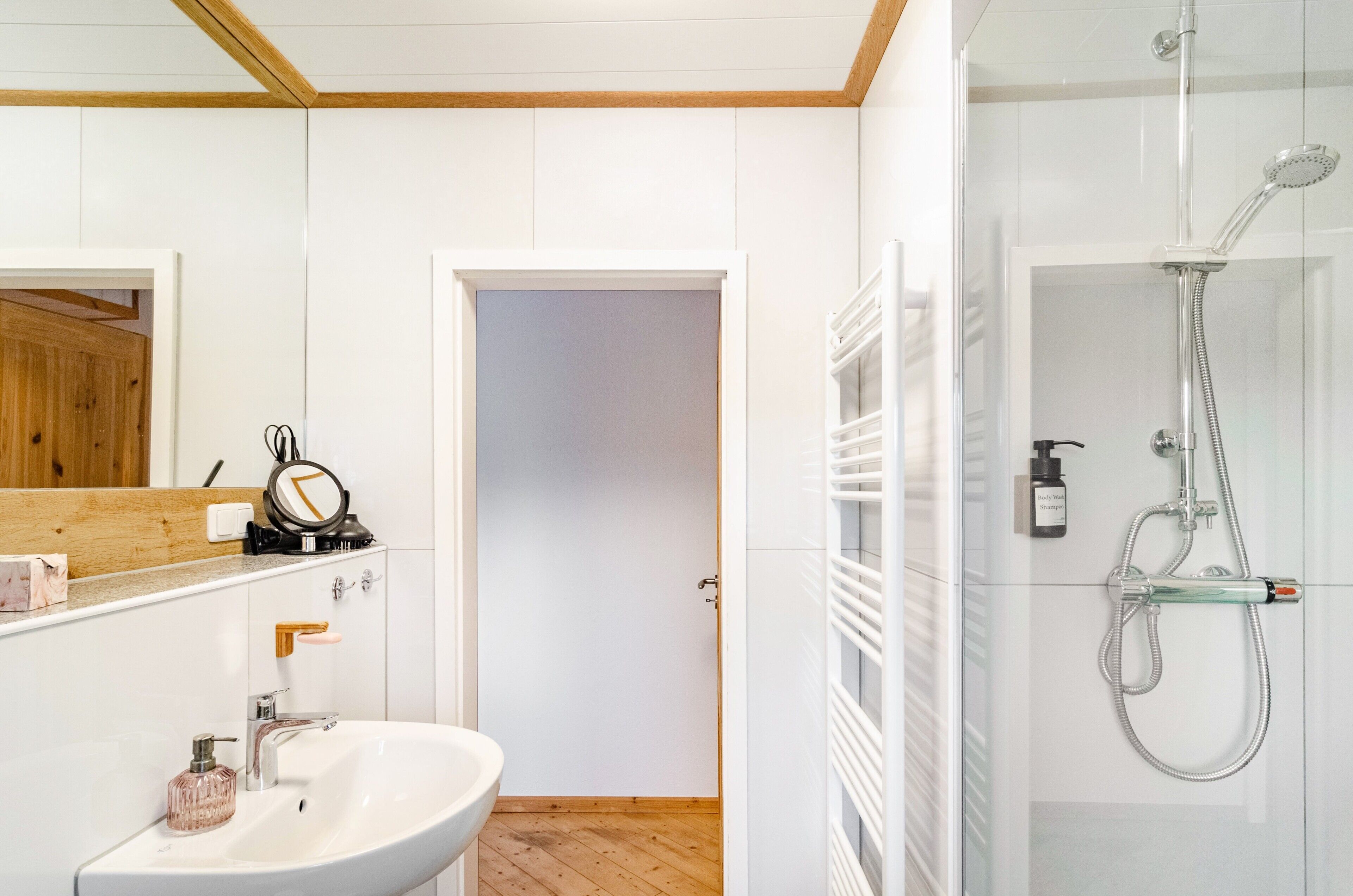 Ein modernes Badezimmer mit Waschbecken, Spiegel und Dusche.