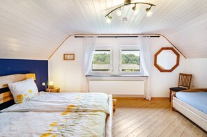 Ein Schlafzimmer mit einem Bett, einem Sessel, einem Fenster mit Blick und einer Deckenleuchte.
