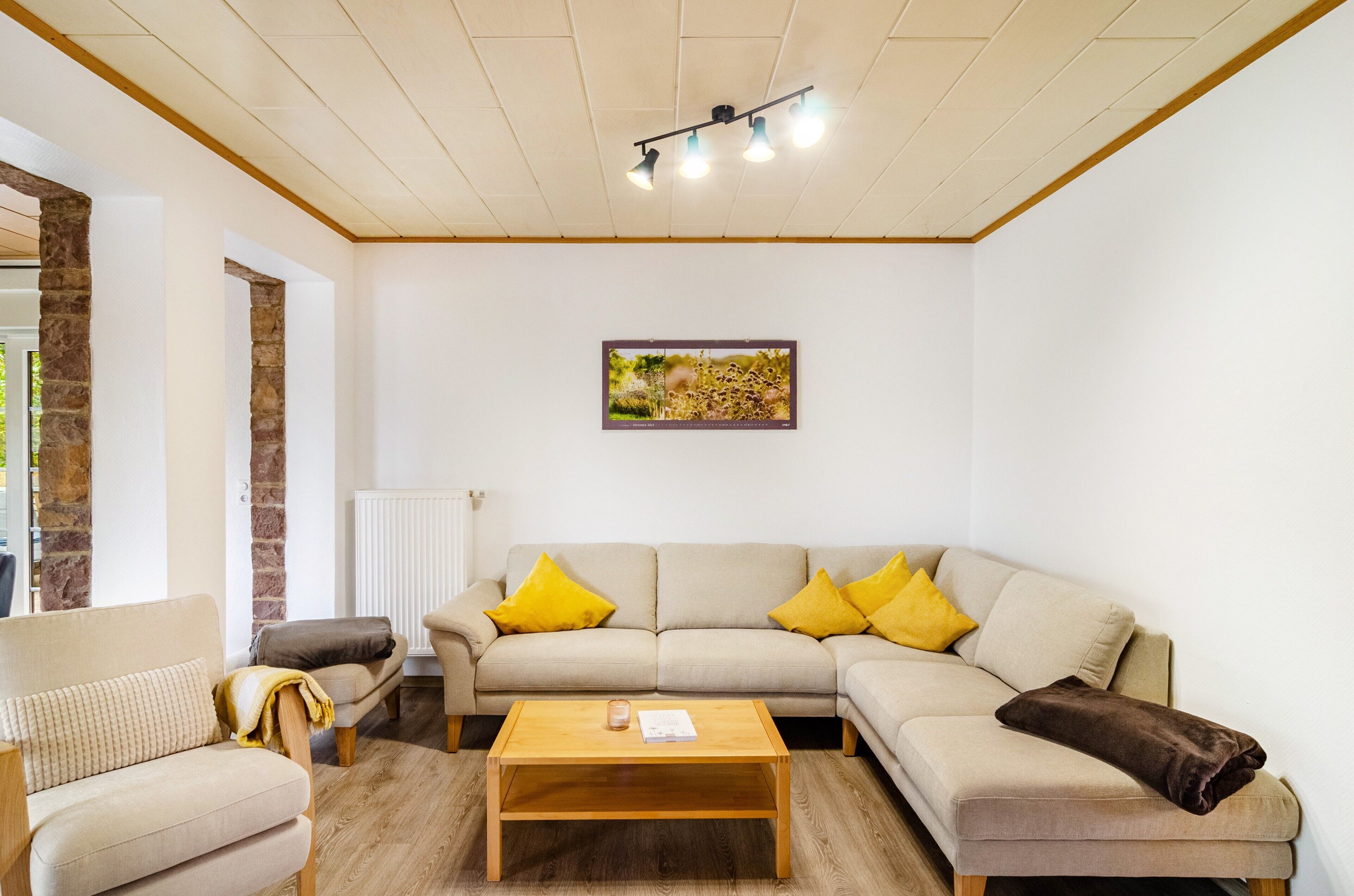 A living room with a sofa, armchairs, a coffee table, and a painting on the wall.