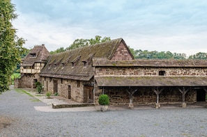 En historisk bygning i sten med et overdækket område og en lille have.