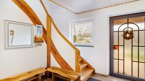 A wooden staircase with a bench, a door with a glass panel, and a small window with a view of buildings.
