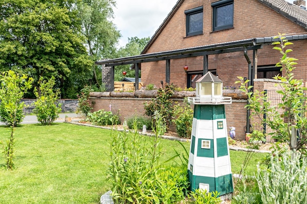 A brick house with a green and white lighthouse-style structure in the garden.