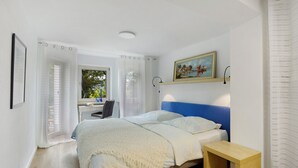 Un dormitorio con una cama, un escritorio y una ventana con cortinas.
