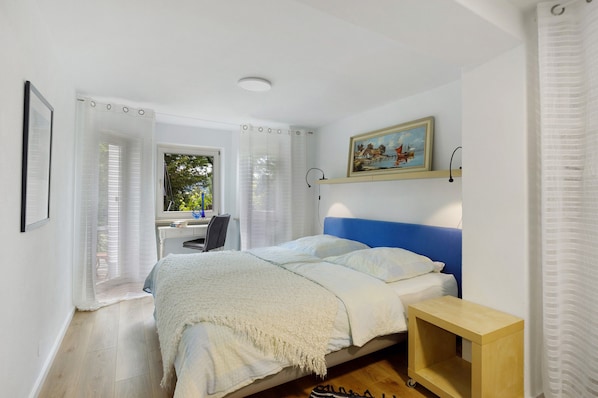 Une chambre à coucher avec un lit, un bureau et une fenêtre avec des rideaux.