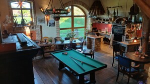 Een gezellige kamer met een pooltafel, een eethoek en een keuken met hangplanten en een grill.
