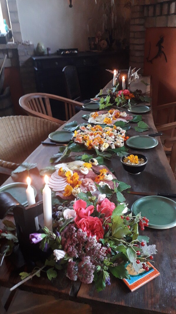 Una larga mesa de comedor con velas, platos y un centro de mesa de flores y follaje.