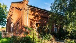 Een bakstenen gebouw met een tuin, een hek en een heldere lucht.