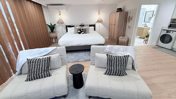 Un dormitorio moderno con una cama, dos sofás, una mesita de centro y un ventilador de techo.