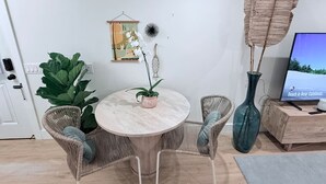 Una mesa redonda de comedor con sillas de mimbre, una planta en maceta y un florero.