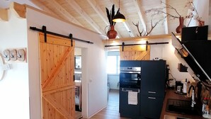 A rustic kitchen with wooden beams, a black refrigerator, and a hanging light fixture. - Holiday Apartment 'Im Garten Gottes' with Air Conditioning and Wi-Fi (Klosterlangheim)