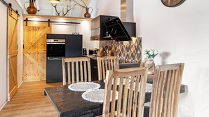 A modern kitchen with a dining area, wooden furniture, and a decorative wall. - Holiday Apartment 'Im Garten Gottes' with Air Conditioning and Wi-Fi (Klosterlangheim)
