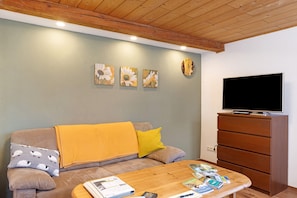 Una sala de estar con sofá, mesa de centro y mueble para la televisión.