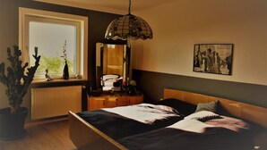 A bedroom with a bed, a dresser, a mirror, a potted plant, and a window. - Apartment 'Familie Graml' with Stunning Views, Large Garden with BBQ and Swing (Hauzenberg)