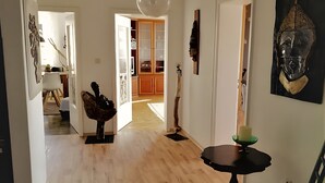 A spacious room with wooden flooring, a dining table with a chair, a hanging light fixture, and a large cabinet in the background. - Apartment 'Familie Graml' with Stunning Views, Large Garden with BBQ and Swing (Hauzenberg)