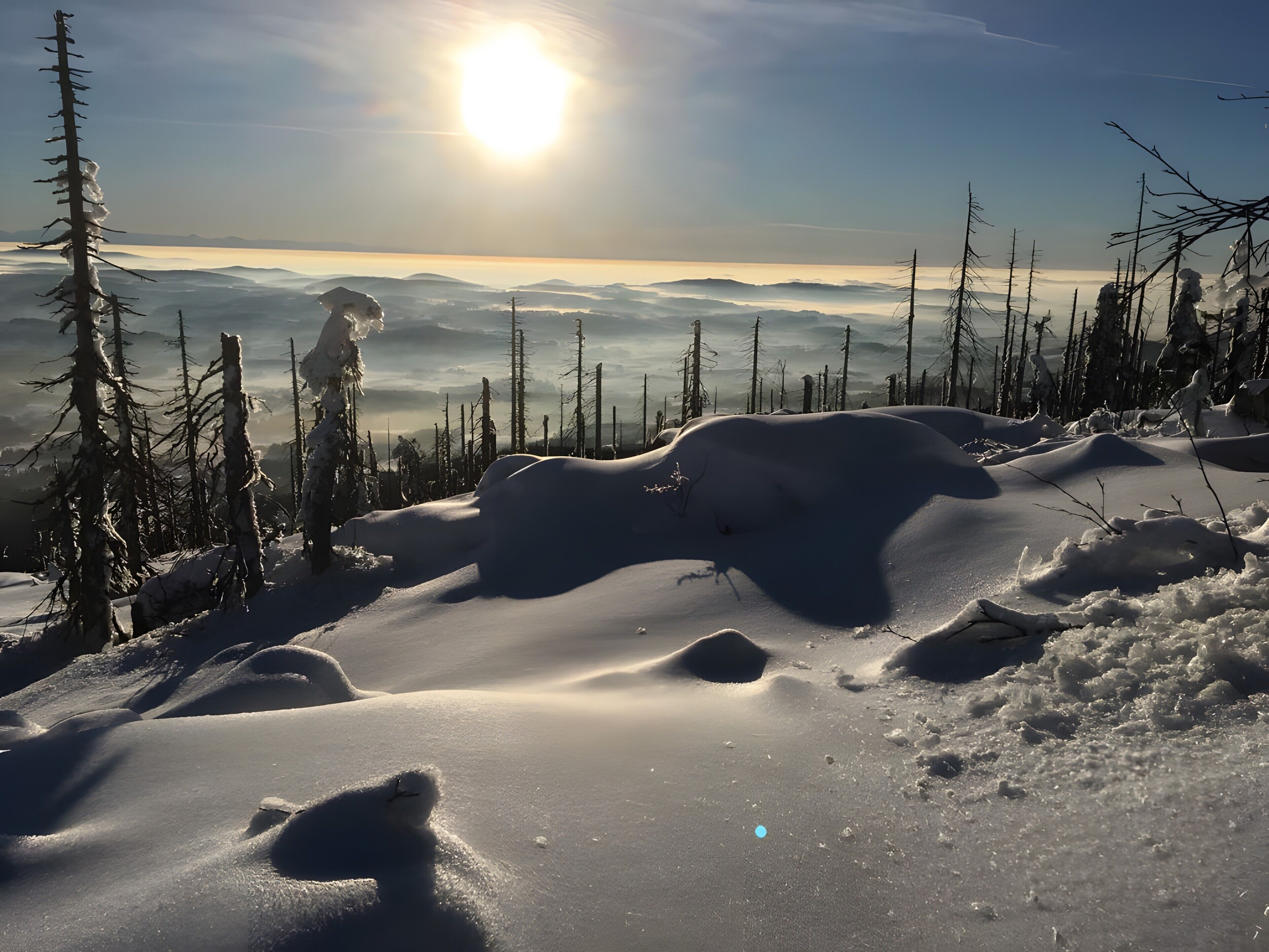 Un paysage enneigé, avec un ciel dégagé et un soleil éclatant.