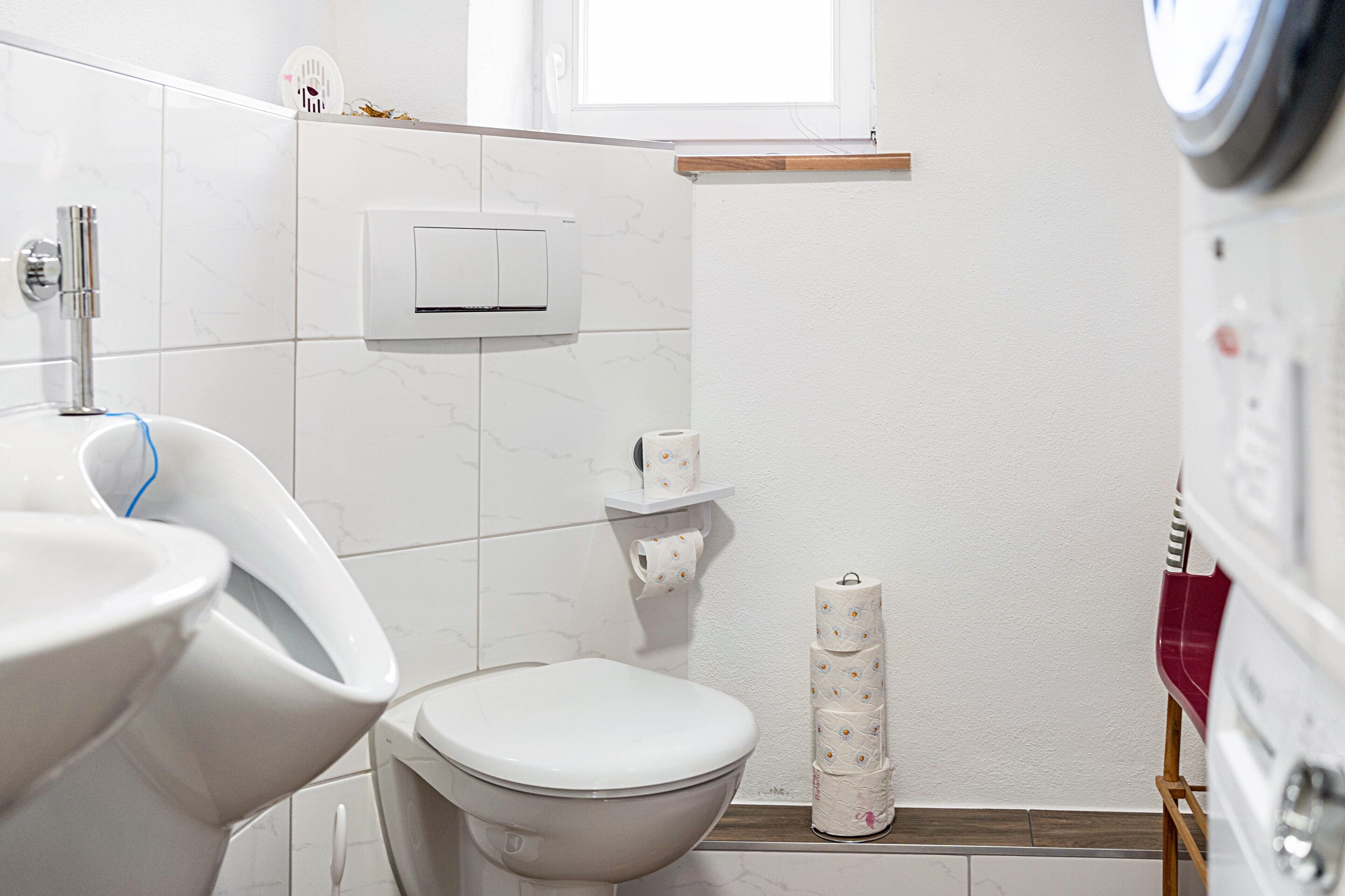 Casa de banho com sanita, bidé e suporte para papel higiénico.