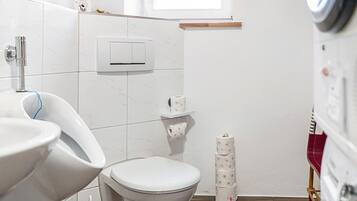 Casa de banho com sanita, bidé e suporte para papel higiénico.