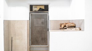 Una habitación con chimenea, una ventana y un estante con leña.