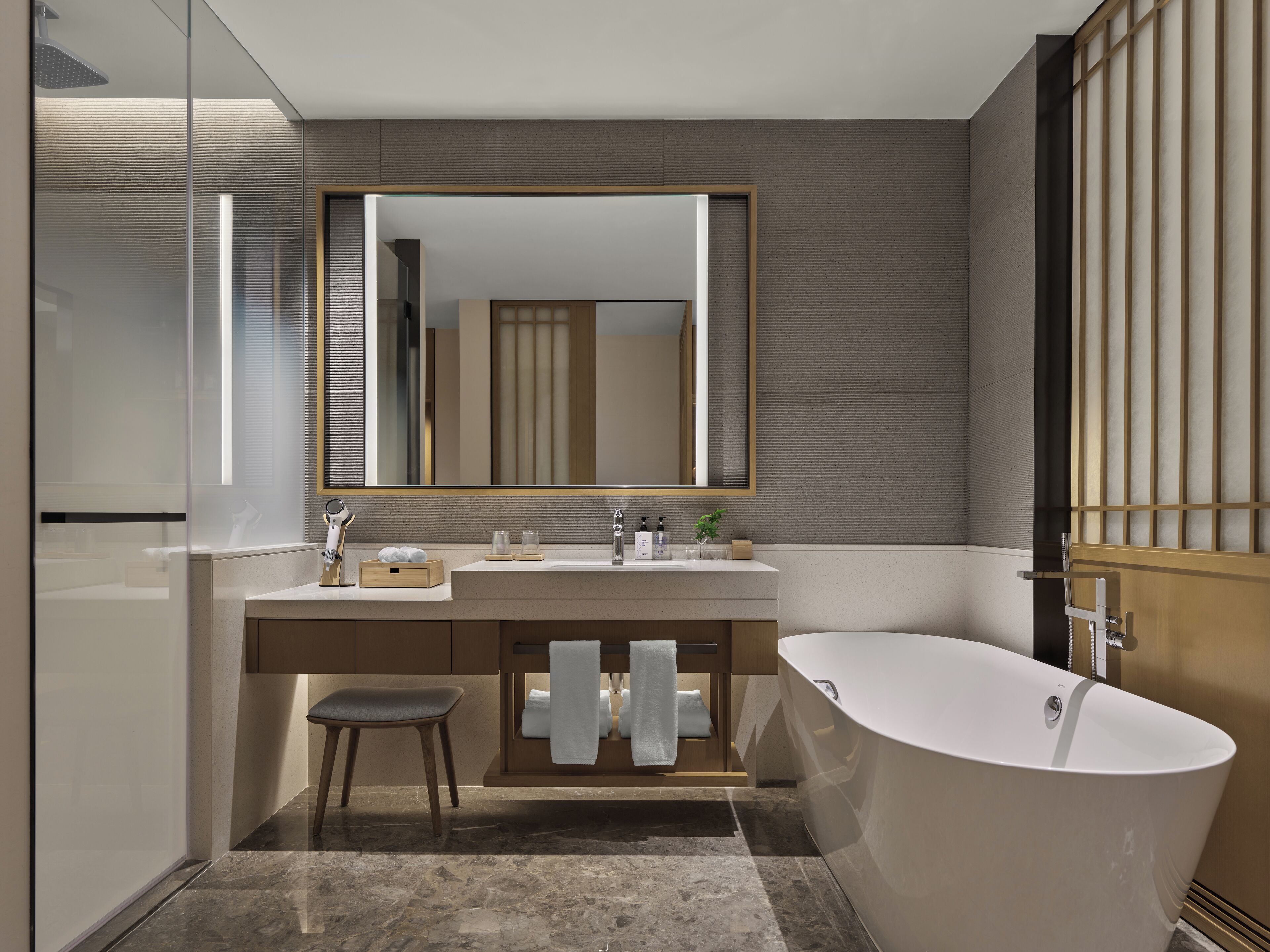 Une salle de bain moderne avec une baignoire sur pieds, un grand miroir et un meuble-lavabo doté d’un porte-serviettes.