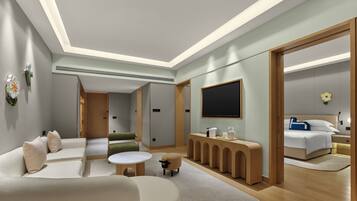 Quarto de hotel moderno com sofá, mesa redonda pequena, um banco de madeira, cama e televisão.