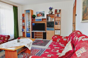 Un salon avec un canapé, une table basse, un téléviseur et des étagères à livres.