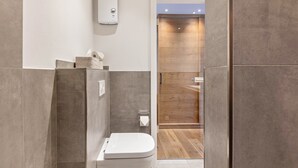 A modern bathroom with a toilet, a hand dryer, and a wooden panel wall. - Apartment with Terrace, Shared Garden, and Wi-Fi (Schmallenberg)