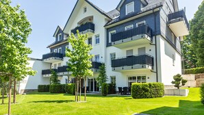 A multi-story residential building with balconies, a well-maintained lawn, and a clear sky. - Apartment with Terrace, Shared Garden, and Wi-Fi (Schmallenberg)