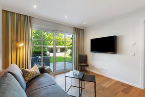 A modern living room with a sofa, a flat-screen TV, and a sliding glass door leading to an outdoor area. - Apartment '1' with Private Terrace, Balcony and Wi-Fi (Schmallenberg)