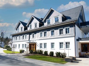 A multi-story building with a symmetrical facade, large windows, and a covered entrance.