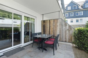 Um pátio com mesa e cadeiras, um painel de madeira e vista para um edifício.