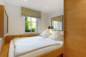 Quarto com cama de madeira, janela com vista e espelho.