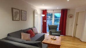 Ein Wohnzimmer mit einer Couch, einem Sessel und einem Holztisch.