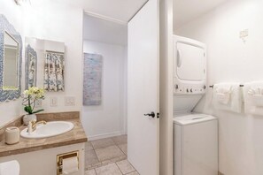 A bathroom with a sink, mirror, and a washing machine.