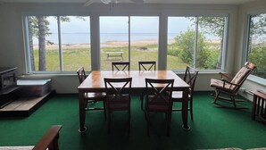 Ein Zimmer mit Esstisch, Stühlen, einem Schaukelstuhl und Blick aufs Meer.