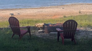 Ein Strand mit zwei Adirondack-Stühlen, die auf den Ozean ausgerichtet sind.